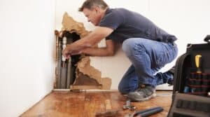 Middle aged man repairing burst water pipe